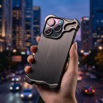 Phone in a brushed metal Titan armor case held against a city skyline at dusk