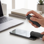 Hand using the Clarity screen cleaner to wipe a phone screen